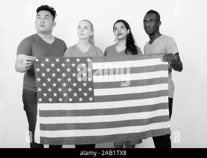 Studio Aufnahme der vielfältigen Gruppe von multi-ethnische Freunde denken, während die amerikanische Flagge zusammen halten Stockfoto