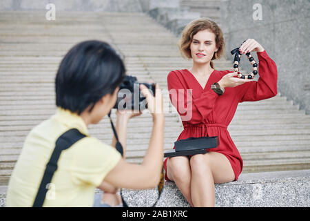 Schöne junge Frau im roten Kleid mit stilvollen massive Halskette posing Stockfoto