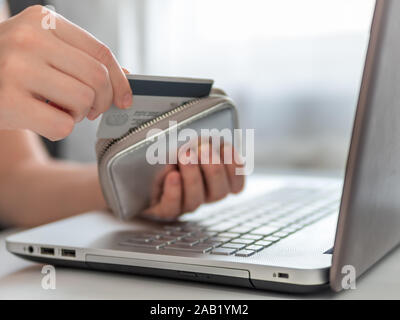Online shopping Konzept. Close-up Woman's Hände Kreditkarte von Portemonnaie in der Nähe von Laptop für Online shopping Stockfoto
