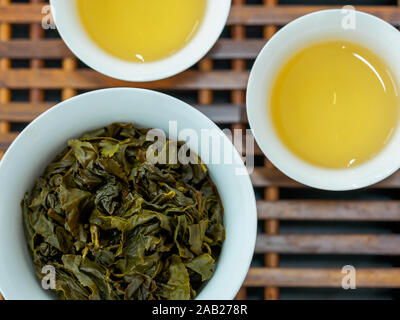 Flach Sicht der Chinesischen grünen Oolong Tee Blätter in einer Porzellantasse/gaiwan gegen einen weißen Hintergrund mit Kopie Raum gebraut Stockfoto
