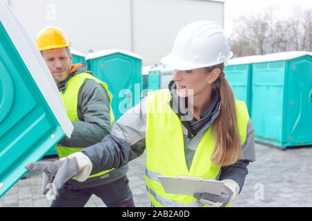 Mitarbeiter laden mobile Toiletten auf Lkw Stockfoto