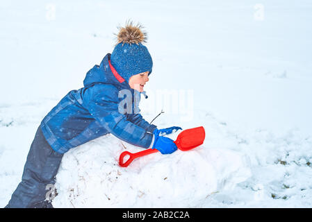 Kleinen Jungen in einen Hut und Handschuhe macht ein Schneemann im Winter Stockfoto