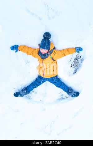 Kleines Mädchen im Schnee zieht ein Engel. Ansicht von oben Stockfoto