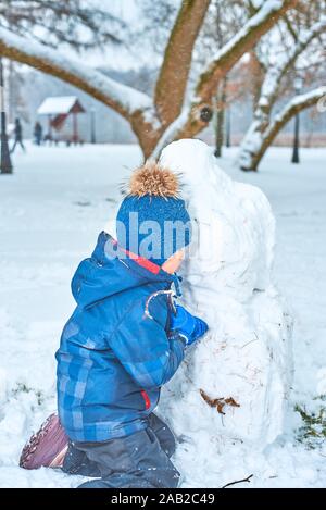 Kleinen Jungen in einen Hut und Handschuhe macht ein Schneemann im Winter Stockfoto