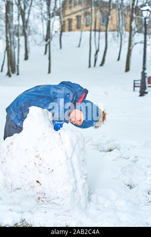 Kleinen Jungen in einen Hut und Handschuhe macht ein Schneemann im Winter Stockfoto