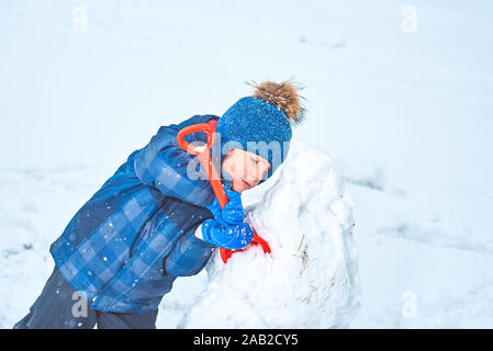 Kleinen Jungen in einen Hut und Handschuhe macht ein Schneemann im Winter Stockfoto