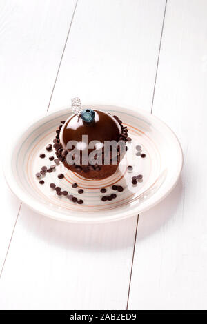 Kleine Kuchen mit unterschiedlicher Füllung auf einer weißen Platte. Weiße Holztisch. Stockfoto