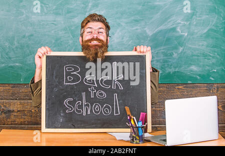 Lehrer oder Schulleiter begrüßt mit blackboard Inschrift zurück in die Schule. Willkommen zurück. Zu Beginn des neuen Schuljahres im September. Lehrer begrüßt neue Schülerinnen und Schüler der Bildungseinrichtung eingeben. Stockfoto