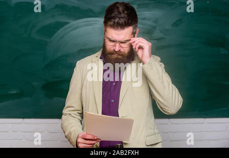 Vorbereitungen für die Prüfung. Lehrer bärtiger Mann halten Dokumente Schiefertafel Hintergrund. Lehrer Schreibarbeit. Schulleiter. Anspruchsvolle Lehrer. Dozent im Klassenzimmer. Erläuterung der Theorie. College und High School. Stockfoto