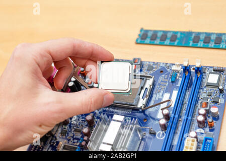 Computer Prozessor Installation in Motherboard socket. Close-up. Schreibtisch. RAM-Modul neben. Stockfoto