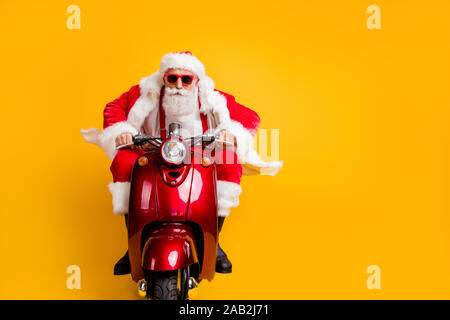 Porträt von Ernst hipster Santa Claus in Red hat mit seinem Roller beeilen rider Fahrt zu x-mas Christmas Party wear shirt Hosenträger über isoliert Stockfoto