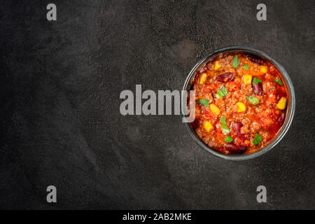 Chili con Carne, Mexikanischen Eintopf mit Bohnen, Fleisch, Mais, Paprika, Overhead shot auf einem schwarzen Hintergrund mit Copyspace Stockfoto
