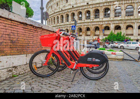 Rom, Italien Rot Uber Jump Pedal-assist Fahrräder geparkt. Dockless Elektrofahrrad sharing System rund mit Korb auf einem Bürgersteig am Colosseum. Stockfoto