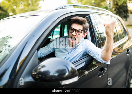 Zornigen Mann ballte seine Faust, sitzen im neuen Auto und Schreien Stockfoto