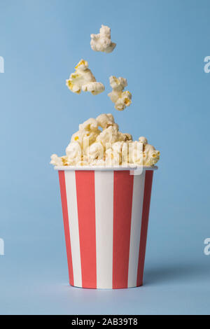 Popcorn in Paper Cup gegen Pastell-blaue Hintergrund minimal kreative Essen Konzept.