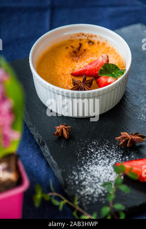 Schüssel mit Crème Brûlée auf einem dunklen Hintergrund. Kochen Dessert. Selektiver Fokus Stockfoto