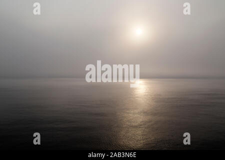 Morgen Sonnenschein glänzt durch Nebel an der Nordsee. Das Meer ist ruhig und die Sonne spiegelt Golden auf seiner Oberfläche. Stockfoto