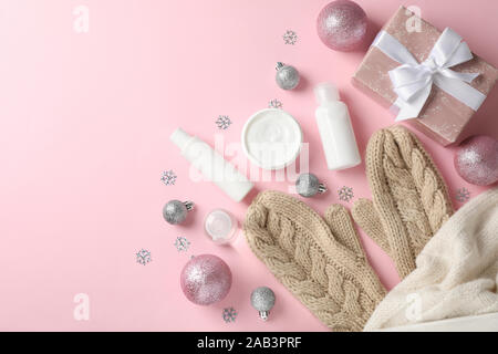 Set Kosmetik, winter Creme für die Haut, warmer Pullover und Handschuhe auf rosa Hintergrund, Platz für Text. Ansicht von oben Stockfoto