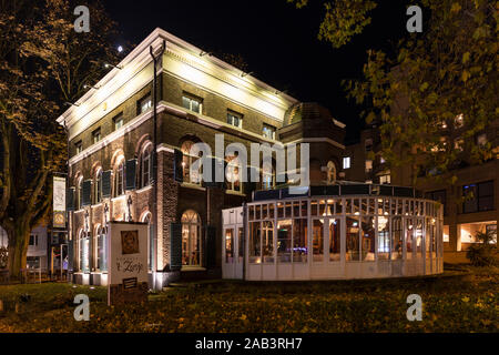 Eindhoven, Niederlande, 7. November 2019. Seitenansicht eines Restaurant Het zusje bei Nacht mit verschiedenen goldenen Farblicht und ein Wintergarten, s Stockfoto