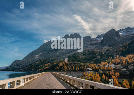 Straße auf der Oberseite des Fedaia Stausee Staudamm am Fuße der Marmolada Berge in Südtirol auf einem sonnigen und klaren Herbsttag Stockfoto