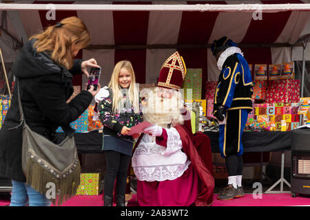 Eindhoven, Niederlande, 23. November 2019. Sinterklaas sein Kostüm und mit einem kleinen Mädchen neben ihm, während für die Kamera posieren und Stockfoto