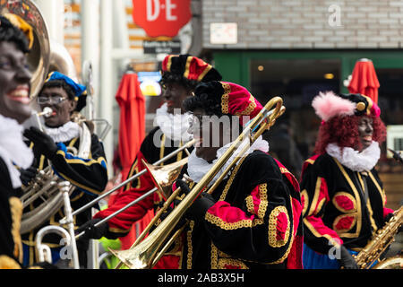 Eindhoven, Niederlande, 23. November 2019. Happy Pieten tragen ihren bunten Kostümen in einer Blaskapelle spielen Sinterklaas Musik ans lächelnd. Stockfoto