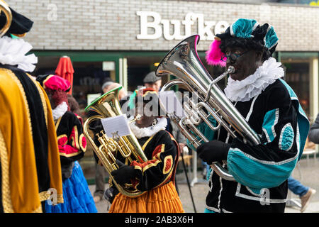 Eindhoven, Niederlande, 23. November 2019. Ein piet tragen ein buntes Kostüm in einer Blaskapelle spielen Sinterklaas Musik auf einer Trompete. Niederländische tra Stockfoto