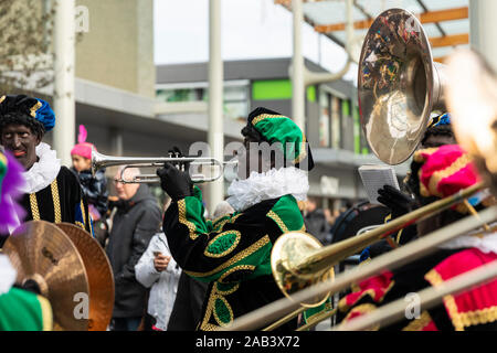 Eindhoven, Niederlande, 23. November 2019. Ein piet tragen ein buntes Kostüm in einer Blaskapelle spielen Sinterklaas Musik auf einer Trompete. Niederländische tra Stockfoto