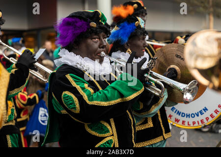 Eindhoven, Niederlande, 23. November 2019. Ein piet tragen ein buntes Kostüm in einer Blaskapelle spielen Sinterklaas Musik auf einer Trompete. Niederländische tra Stockfoto