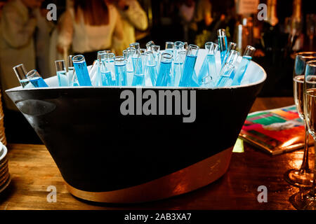 Trinken Blau in ein Becherglas, das in einen Eimer mit Sekt mit Eis sind, steht auf einem Holztisch. Stockfoto