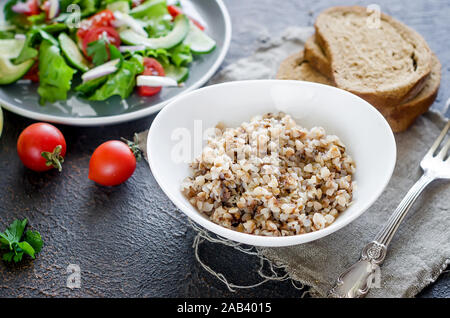 Hot Buchweizen Porridge mit schmelzender Butter in der Platte andHealthy vegetarischen Salat von frischen Gemüse für lanch auf Tabelle, Ansicht von oben, kopieren Raum Gesunde f Stockfoto