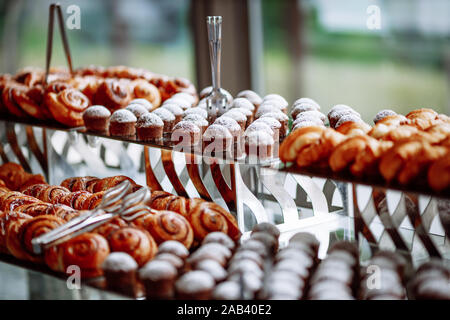 Vielen leckeren Croissants, Muffins und Brötchen sind auf den Glastisch. Stockfoto