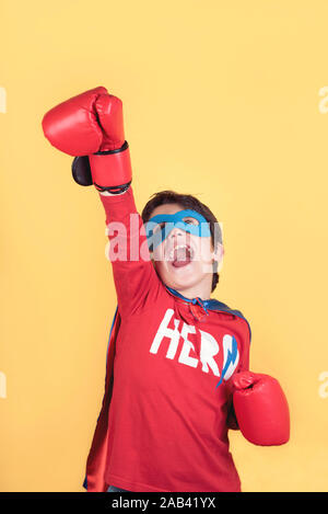 Superhelden, Portrait eines Jungen in Superhelden Kostüm auf gelbem Hintergrund Stockfoto