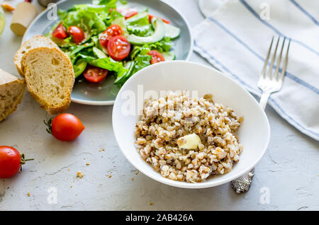 Hot Buchweizen Porridge mit schmelzender Butter in der Platte andHealthy vegetarischen Salat von frischen Gemüse für lanch auf Tabelle, Ansicht von oben, kopieren Raum Gesunde f Stockfoto