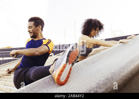 Interracial Paar junge Läufer stretching auf Stadt Treppen vor dem Ausführen, Fitness, urbane Sportarten Workout und gesunden Lebensstil Konzept, kopieren Raum Stockfoto