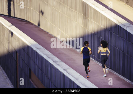 Rückansicht eines interracial Paar Läufer Joggen auf der Straße in einem modernen Umfeld der Wände. Fitness, urbane Sportarten Training und gesunde lif Stockfoto
