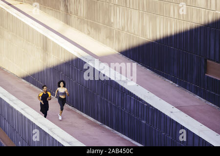 Glückliche junge Frau und Sport Mann laufen auf der Straße in einem modernen Umfeld der Wände. Fitness, urbane Sportarten Workout und gesunden Lebensstil anhand von quantitativen Simulatio Stockfoto