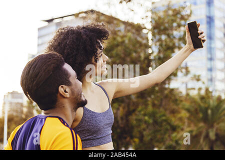 Porträt einer schönen lateinischen Frau und Mann in Schwarz ein selfie mit einem Mobiltelefon, während ein Rest im Training, Technik im Sport und gesunde li Stockfoto