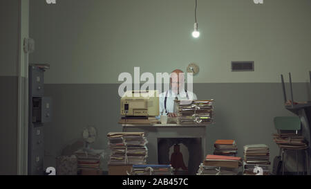 Frustriert Vintage Style Geschäftsmanns, der in einer heruntergekommenen alten Büro, er ist mit papework überlastet Stockfoto