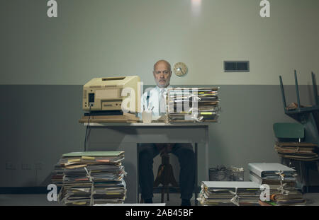 Frustriert Vintage Style Geschäftsmanns, der in einer heruntergekommenen alten Büro, er ist mit papework überlastet Stockfoto