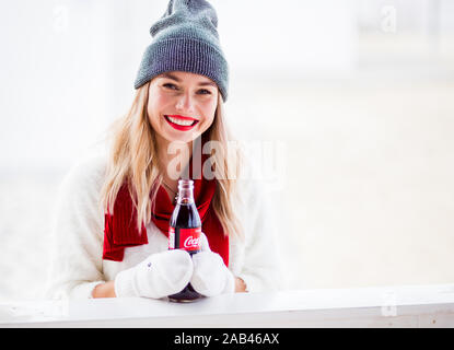 Russland, Sotschi - November 23, 2019: Pretty girl Holding in den Händen zwei Coca Cola Flaschen lachend und an chirstmas Tag Stockfoto