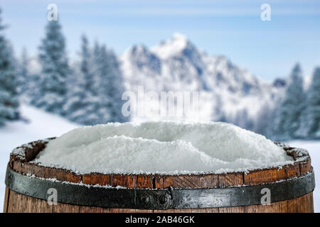 Alten Holzfass top mit Schnee und die schneebedeckten Berge im Hintergrund. Stockfoto