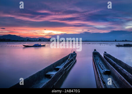 Berglandschaft, See- und Bergkette, großer See und Boot. Schöner Sonnenuntergang spiegelt sich im Lak See, Buon Me Thuot, Vietnam wider Stockfoto