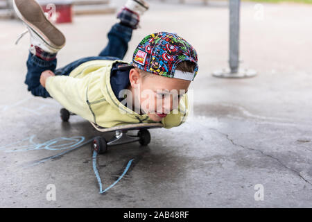 Eine süße kleine Jungen mit ADHS, Autismus, Asperger Syndrom Reiten um den Skatepark, Chillen und Spaß beim Trainieren und Energie Stockfoto