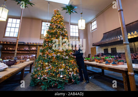 Brighton UK 25. November 2019 - Mitarbeiter Karen Antoni fügt einige Dekorationen für den Weihnachtsbaum in der Küche der Royal Pavilion in Brighton. Eine Reihe von geschmückte Bäume und ein Schlitten für Besucher ausprobieren kann um die berühmten seaside Retreat von König George IV diese festliche Jahreszeit gebaut. Foto: Simon Dack/Alamy leben Nachrichten Stockfoto