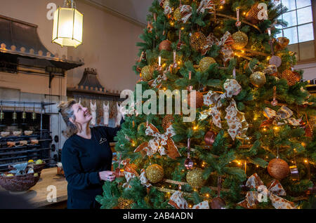 Brighton UK 25. November 2019 - Mitarbeiter Karen Antoni fügt einige Dekorationen für den Weihnachtsbaum in der Küche der Royal Pavilion in Brighton. Eine Reihe von geschmückte Bäume und ein Schlitten für Besucher ausprobieren kann um die berühmten seaside Retreat von König George IV diese festliche Jahreszeit gebaut. Foto: Simon Dack/Alamy leben Nachrichten Stockfoto