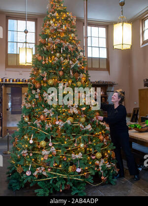 Brighton UK 25. November 2019 - Mitarbeiter Karen Antoni fügt einige Dekorationen für den Weihnachtsbaum in der Küche der Royal Pavilion in Brighton. Eine Reihe von geschmückte Bäume und ein Schlitten für Besucher ausprobieren kann um die berühmten seaside Retreat von König George IV diese festliche Jahreszeit gebaut. Foto: Simon Dack/Alamy leben Nachrichten Stockfoto