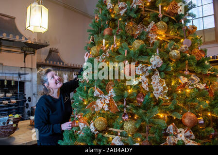 Brighton UK 25. November 2019 - Mitarbeiter Karen Antoni fügt einige Dekorationen für den Weihnachtsbaum in der Küche der Royal Pavilion in Brighton. Eine Reihe von geschmückte Bäume und ein Schlitten für Besucher ausprobieren kann um die berühmten seaside Retreat von König George IV diese festliche Jahreszeit gebaut. Foto: Simon Dack/Alamy leben Nachrichten Stockfoto