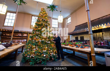 Brighton UK 25. November 2019 - Mitarbeiter Karen Antoni fügt einige Dekorationen für den Weihnachtsbaum in der Küche der Royal Pavilion in Brighton. Eine Reihe von geschmückte Bäume und ein Schlitten für Besucher ausprobieren kann um die berühmten seaside Retreat von König George IV diese festliche Jahreszeit gebaut. Foto: Simon Dack/Alamy leben Nachrichten Stockfoto