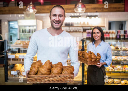 Schöner Mann lächelnd, während sie Croissants am Morgen Bärtigen Stockfoto